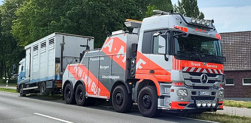 Abschleppfahrzeug von AMF schleppt einen LKW auf einer Landstraße ab.
