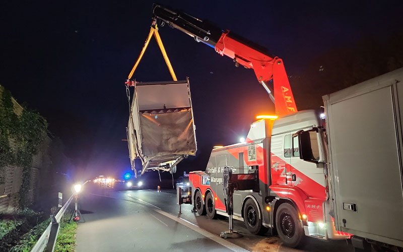 amf-abschleppdienst-bergungsdienst-2 Ein Ladekranfahrzeug von AMF hebt einen LKW-Anhänger auf einer Autobahn hoch.