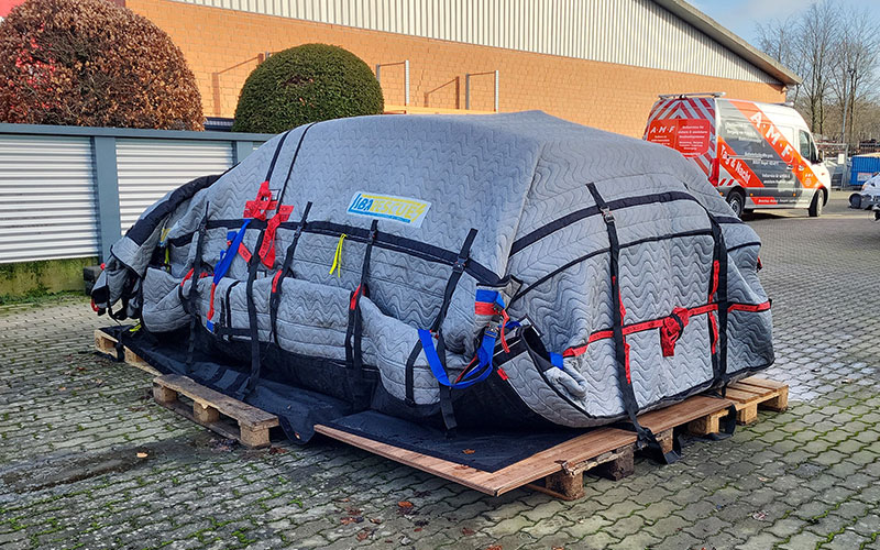 amf-abschleppdienst-elektromobilitaet-schadensfall-3 Mit Sicherheitsdecken abgedecktes Elektroauto auf Pflastersteinen.