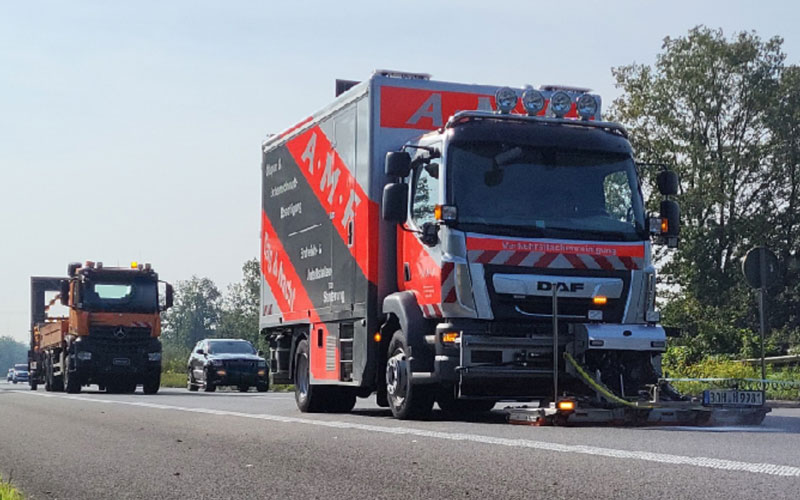 amf-abschleppdienst-verkehrsflaechenreinigung-1 Kehrmaschine von AMF reinigt die Autobahn. Dahinter fahren weitere Fahrzeuge.